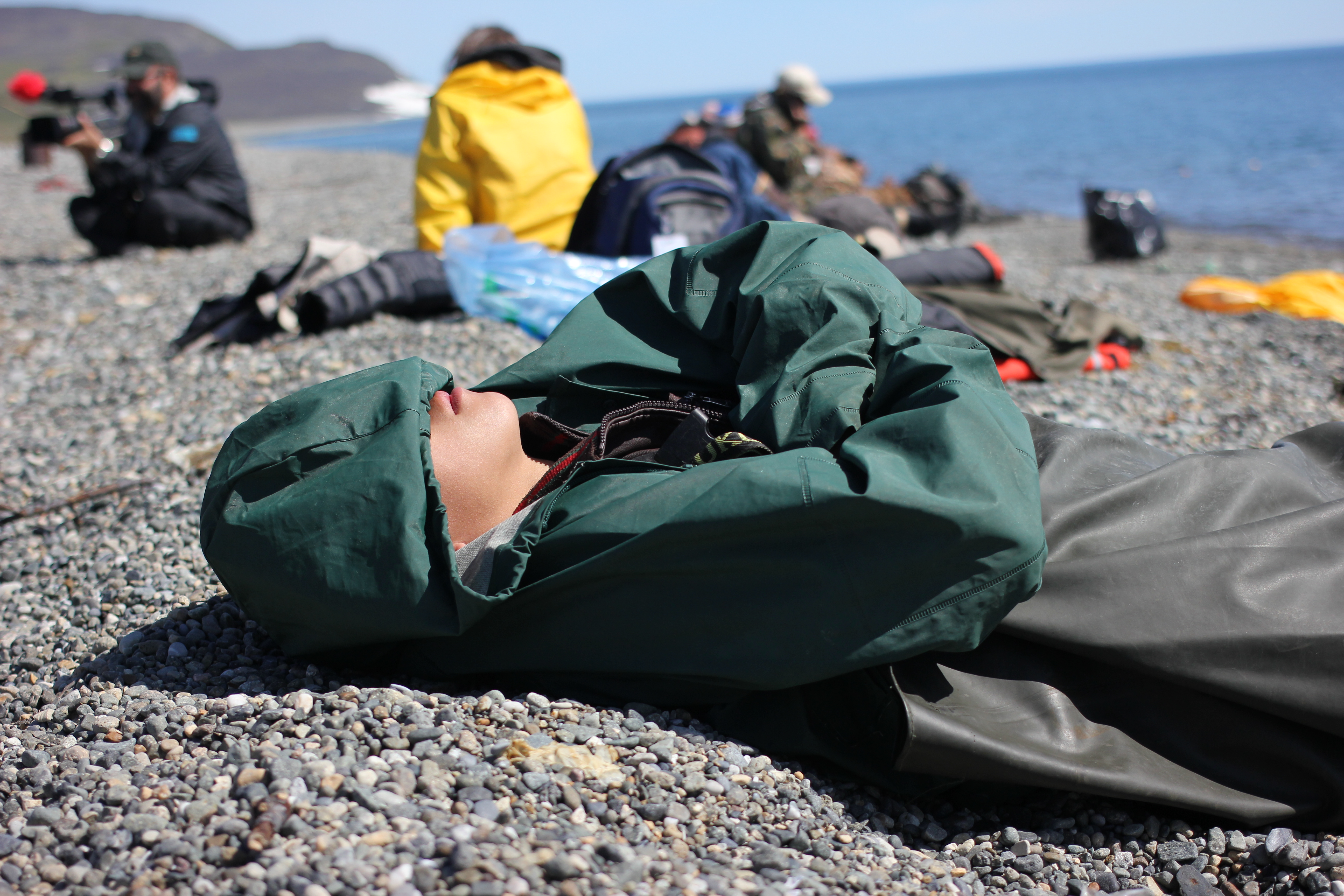 A young boat driver naps on the shore during a brief stop in Yanrakynnot, Chukotka, July 2014. While traveling the coastline, the Diomede Island Family Reunion expedition stopped frequently to check in with border guards along the way. (Kirsten Swann / Alaska Dispatch News)