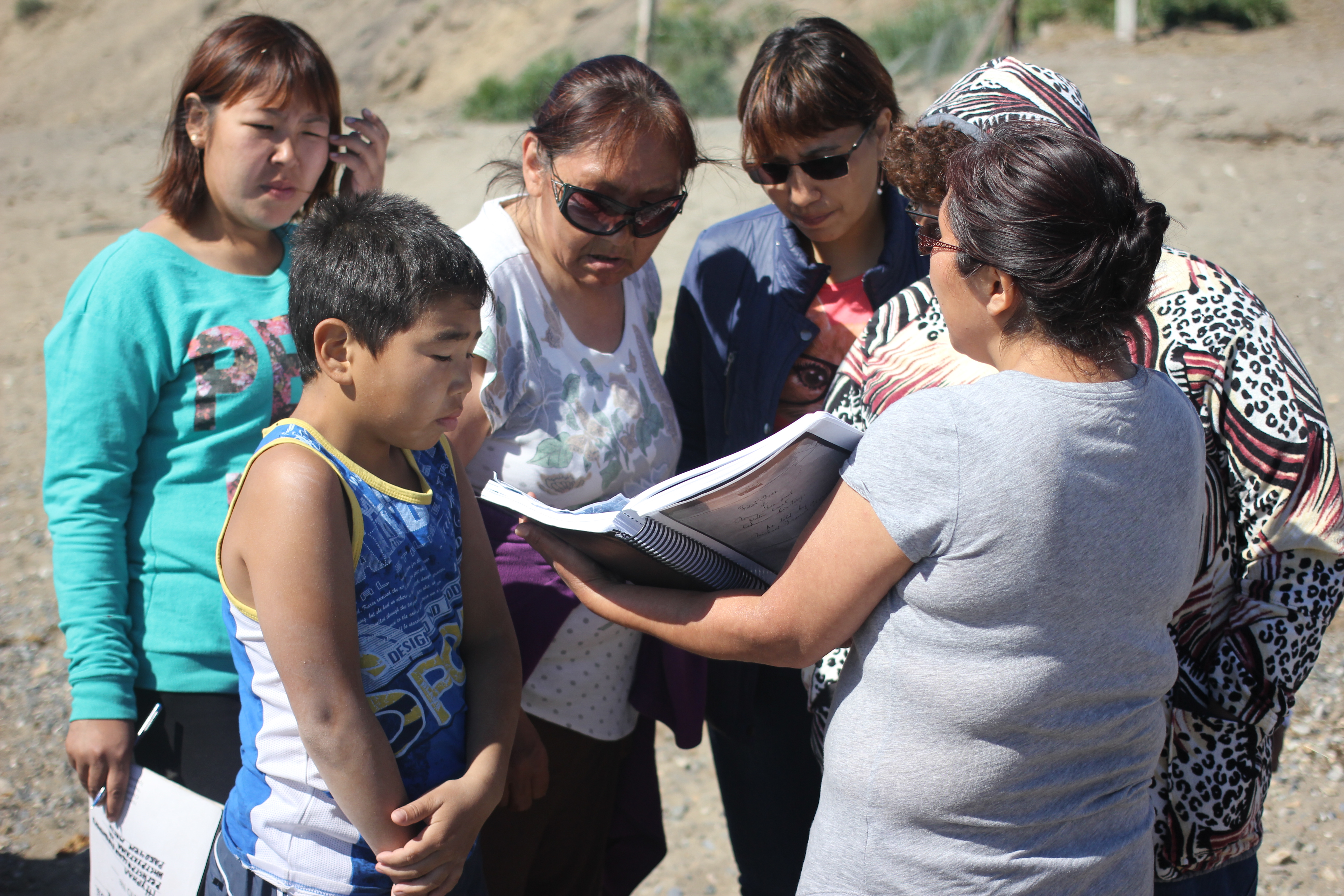 Etta Tall shows her grandfather’s book to residents of Lorino, Chukotka, July 2016. Her grandfather wrote extensively about life on Big Diomede, and Tall hoped to find people who recognized some of the family names documented in the book. (Kirsten Swann / Alaska Dispatch News)