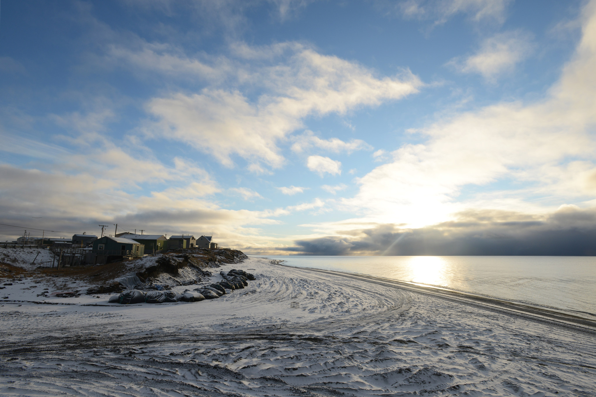 Following a snowstorm, the sun makes an evening appearance at the bluffs that include the Ukkuqsi archaeological site on Monday, September 21, 2015, in Barrow. Sand bags help protect the site, which once again yielded human remains following a late-August storm. (Erik Hill / Alaska Dispatch News)