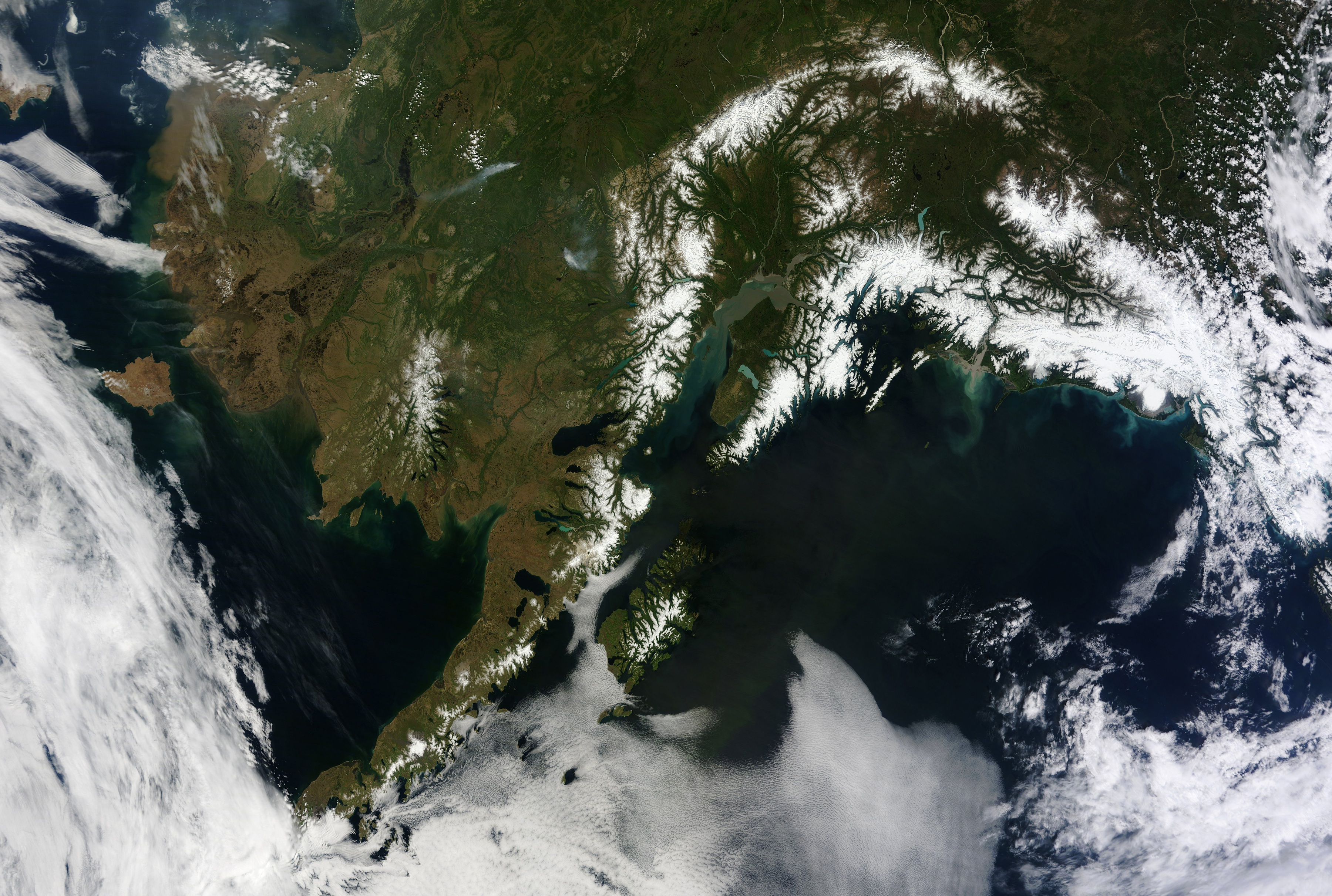 The absence of clouds exposed a striking tapestry of water, ice, land, forests, and even wildfires of Alaska. Snow-covered mountains such as the Alaska Range and Chugach Mountains were visible in southern Alaska, while the arc of mountains that make up the Brooks Range dominated the northern part of the state. The Yukon River -- the longest in Alaska and the third longest in the United States -- wound its way through the green boreal forests that inhabit the interior of the state. Plumes of sediment and glacial dust poured into the Gulf of Alaska from the Copper River. And Iliamna Lake, the largest in Alaska, was ice free. (Jeff Schmaltz/NASA/MCT)