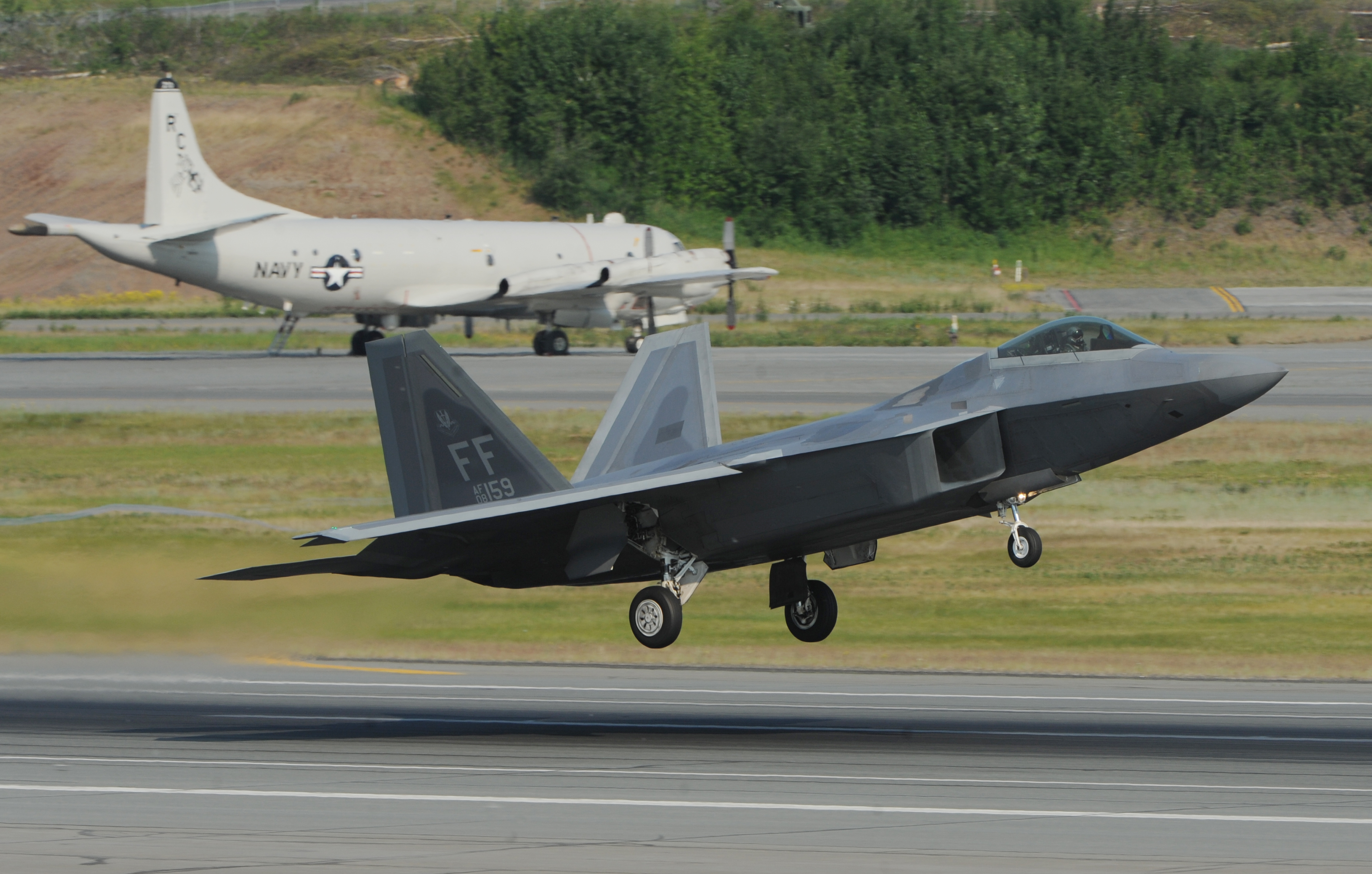 A F-22 Raptor from the 1st Fighter Squadron at Langley Air Force Base takes off from Joint Base Elmendorf-Richardson near Anchorage on Tuesday morning, June 23, 2015, while participating in Alaska's premier joint training exercise Northern Edge.  A Navy P-3 Orion is in the background. (Bill Roth / Alaska Dispatch News)