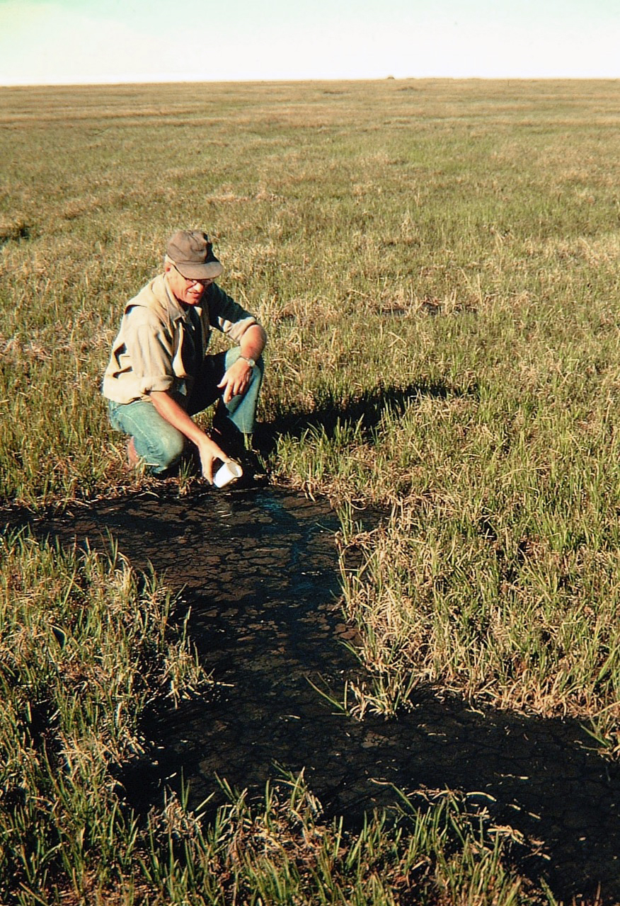 Bob Detterman collects a sample at the Angun Point tar seep located in ANWR’s coastal plain, east of the village of Kaktovik, in 1975. Detterman worked for the U.S. Geological Survey along with Gil Mull, who took the photo. The tar, seen as a black pool, is weathered oil. (Gil Mull/USGS)