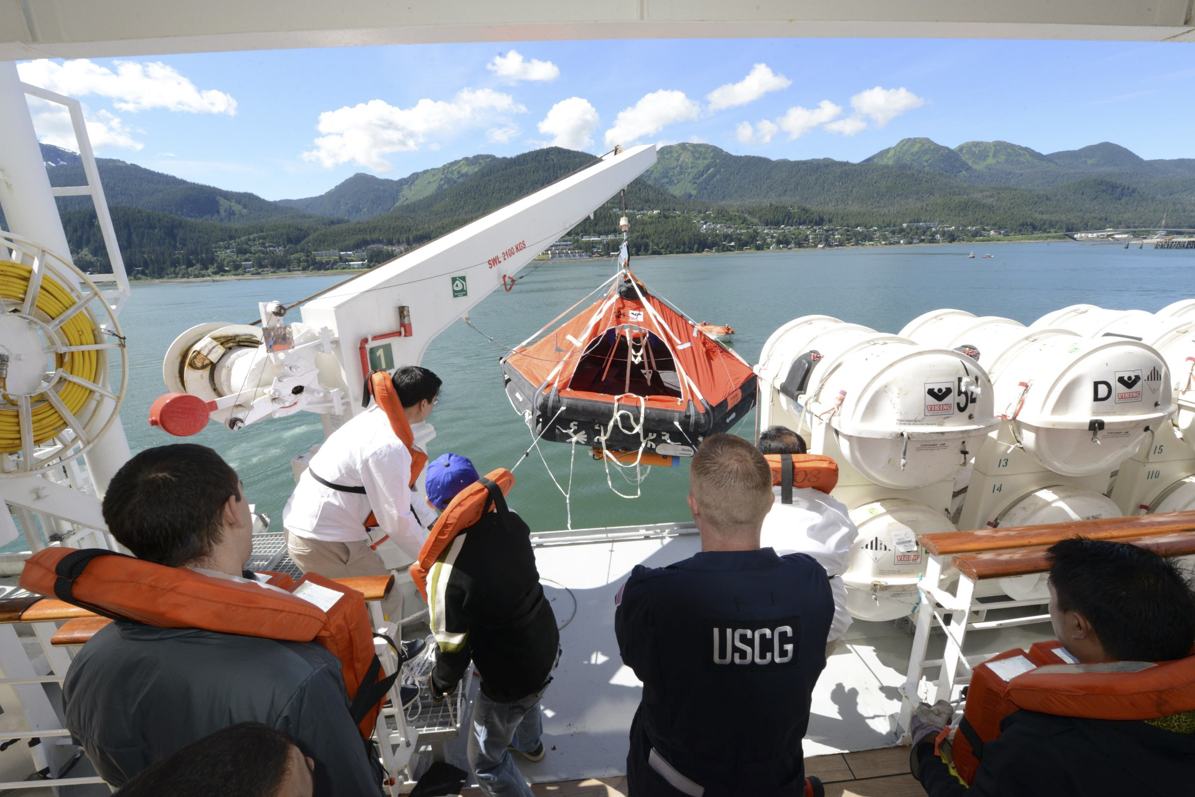 Lt. Ryan Butler, center back to camera, of the U.S. Coast Guard observes crew members of the Crystal Serenity as they test a crane and life raft before a Northwest Passage cruise,  Juneau, Alaska, June 22, 2016. As global warming reduces the extent of sea ice in the Arctic, more ships will be plying waters farther north, which raises concerns about ship safety. (Petty Officer 2nd Class Jon-Paul Rios / U.S Coast Guard via The New York Times) 