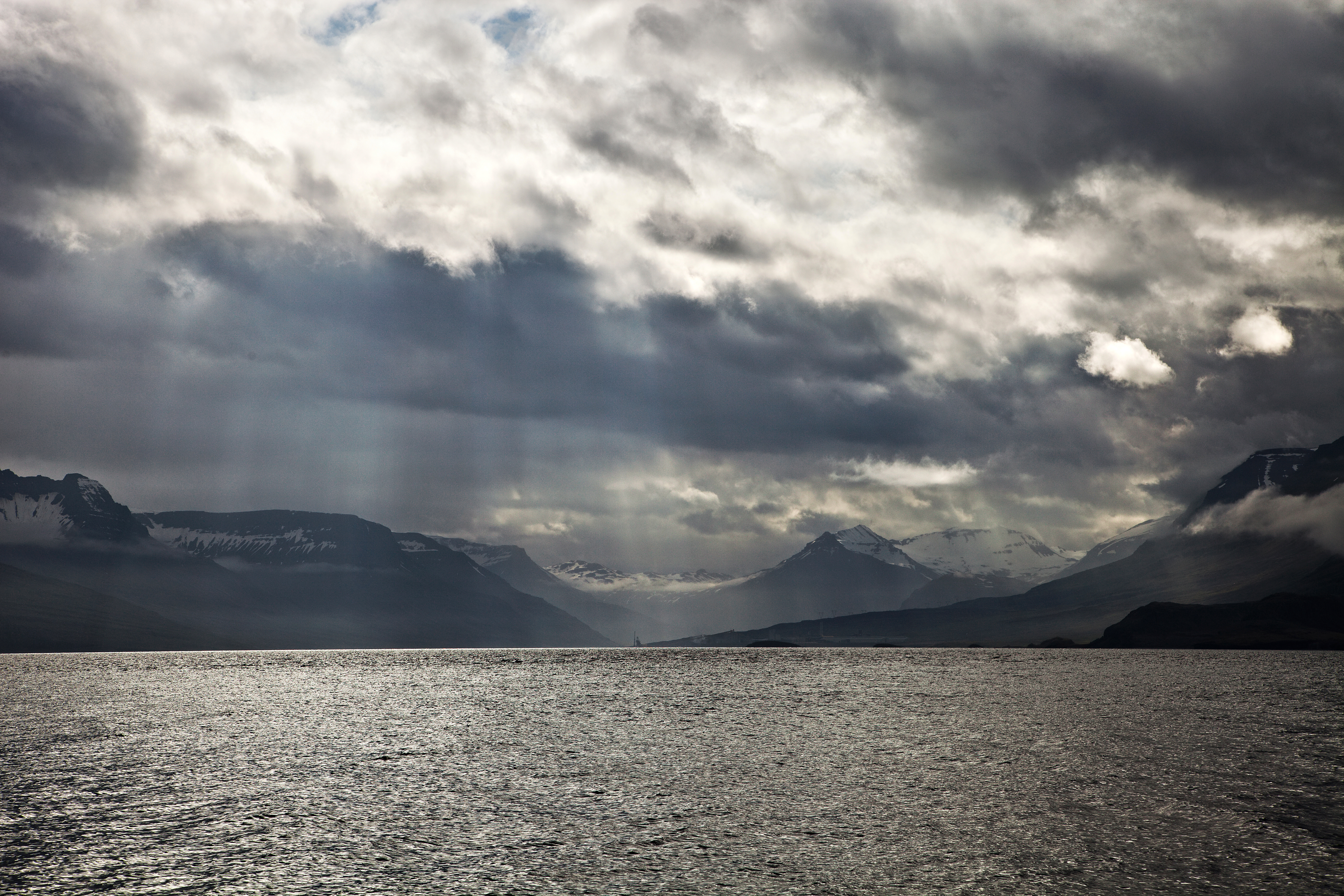 Beautiful steel waters of Reydafjordur with rays of the sun, and mountains in the background. (Getty)