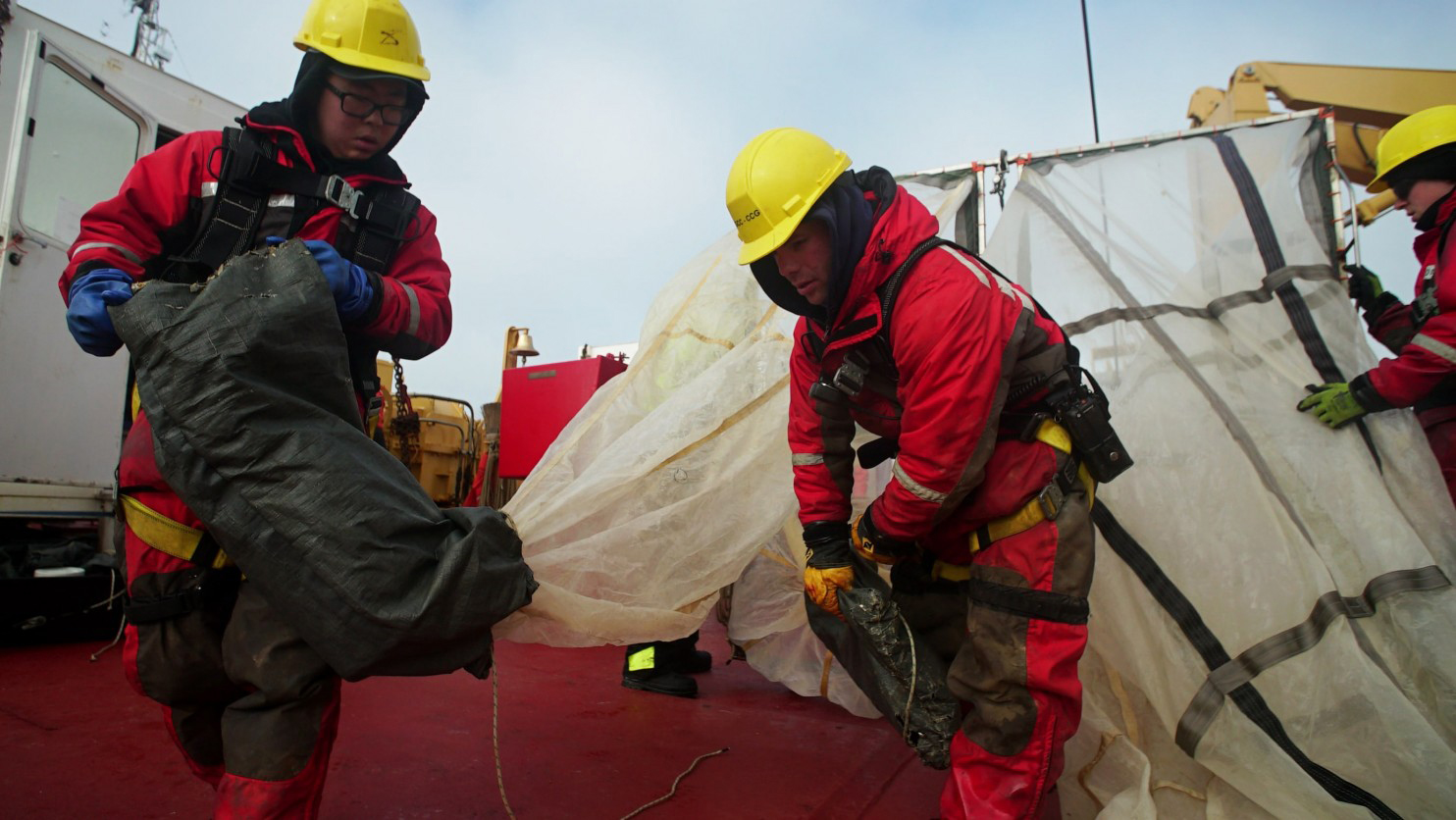 Jasmin Beauregard, left, and Hugo Jacques of the Canadian coast guard prepare nets in the Queen Maud Gulf. The nets are used to scrape the seafloor and capture specimens for researchers to study. (Alice Li / The Washington Post)